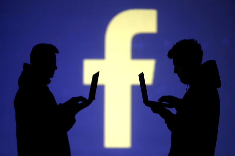 © Reuters. Foto de archivo. Siluetas de usuarios de computadoras portátiles junto a una proyección de pantalla del logotipo de Facebook en esta ilustración