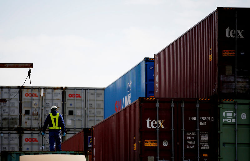 © Reuters. FILE PHOTO: A man works to load a container on a truck at an industrial port in Tokyo