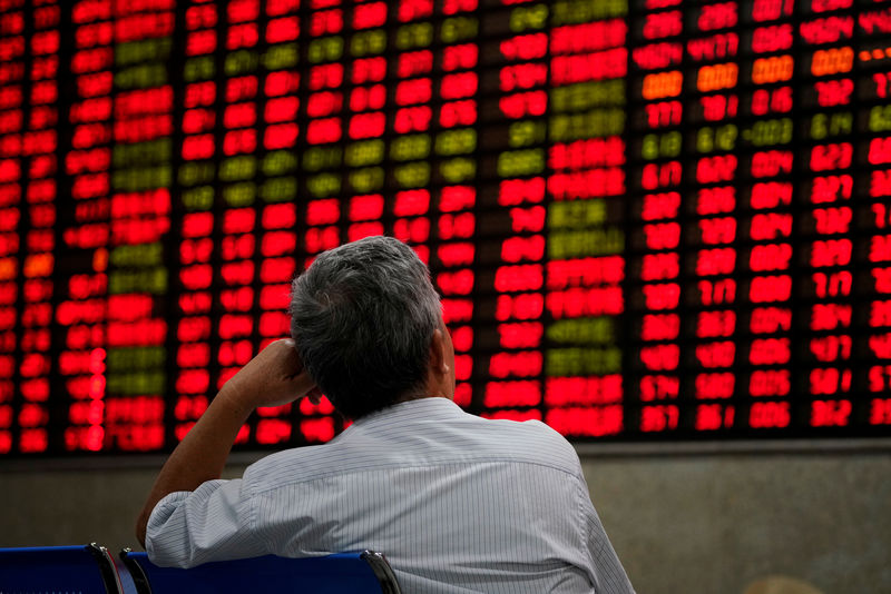 © Reuters. FILE PHOTO:  An investor looks at an electronic board showing stock information at a brokerage house in Shanghai