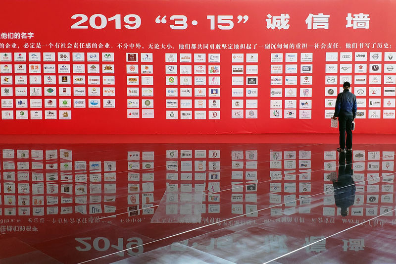 © Reuters. Man stands in front of an "integrity wall" at a consumer goods expo which opens a day ahead of World Consumer Rights Day, in Dalian