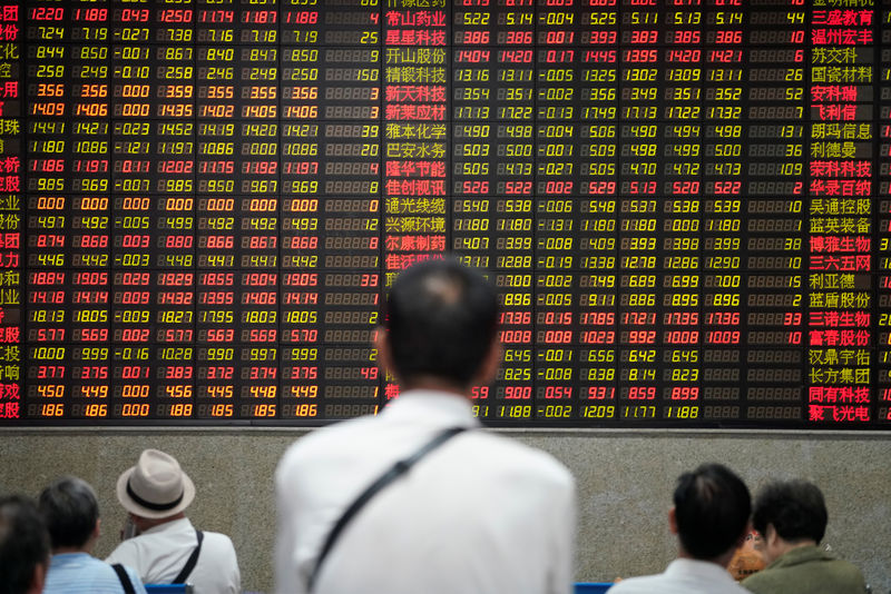 © Reuters. FILE PHOTO: People look at an electronic board showing stock information at a brokerage house in Shanghai