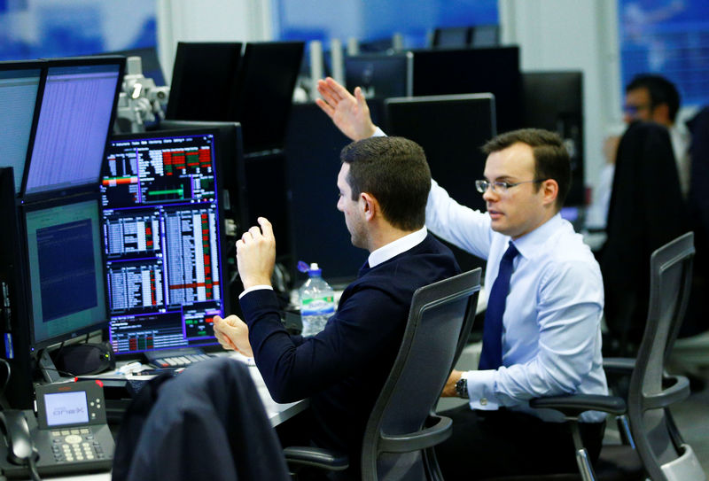 © Reuters. FILE PHOTO  - Traders work at their desks whilst screens show market data at CMC Markets in London