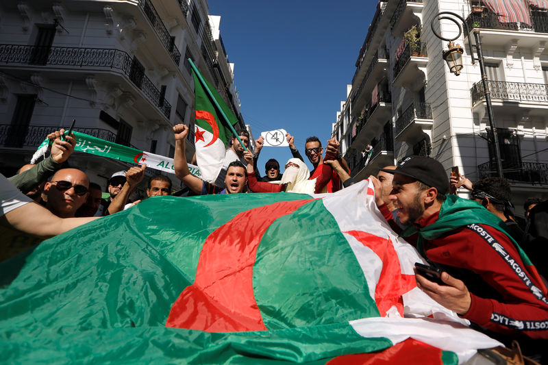 © Reuters. People carry their national flags as they protest over President Abdelaziz Bouteflika's decision to postpone elections and extend his fourth term in office, in Algiers
