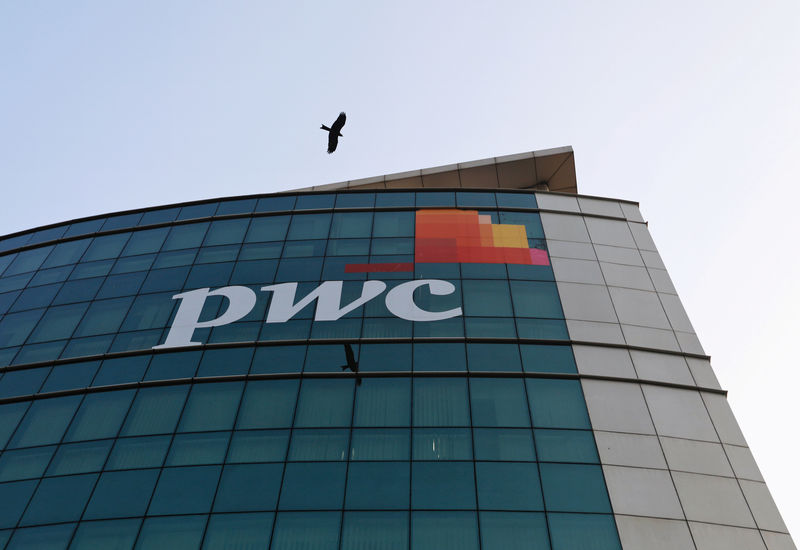 © Reuters. A bird flies past the logo of Price Waterhouse installed on the facade of its office in Mumbai