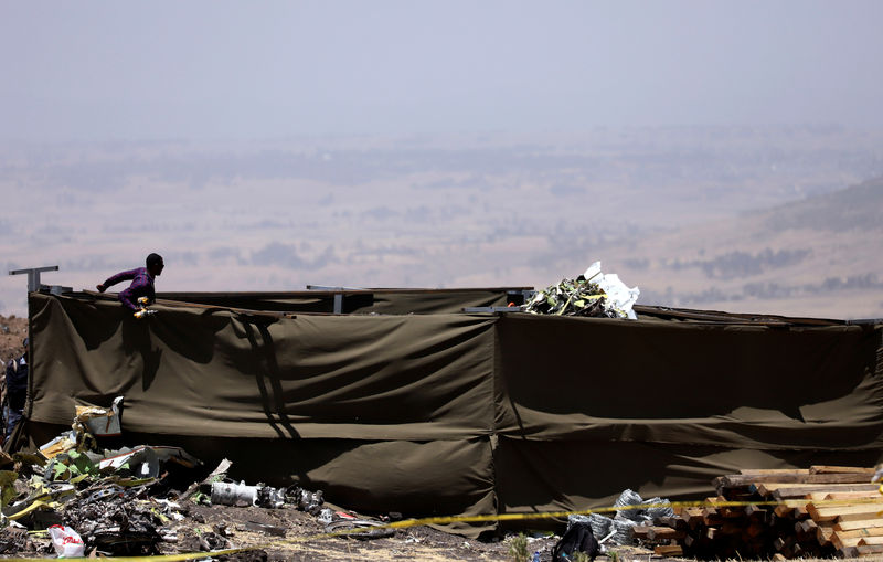 © Reuters. Member of a rescue team stands at the secured wreckage of the Ethiopian Airlines Flight ET 302 plane crash, near the town Bishoftu