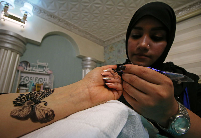 © Reuters. A woman applies henna to the hands of a customer inside her beauty shop in Basra