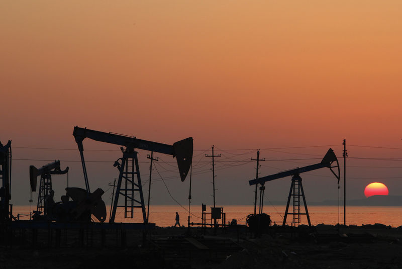 © Reuters. Pump jacks are silhouetted against the rising sun on an oilfield in Baku