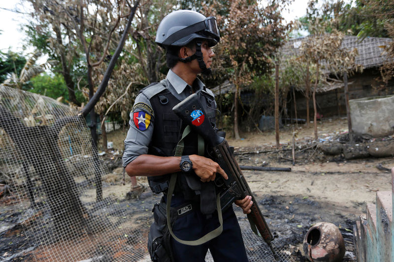 © Reuters. Police officer guards near a house which was burnt down during the last days of violence in Maungdaw