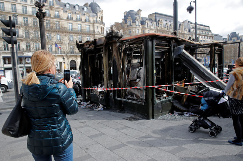 © Reuters. People take pictures of a newspaper kiosk burned during the last "yellow vests" protest on the Champs Elysees avenue in Paris