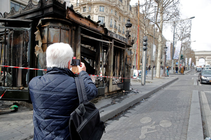 © Reuters. Homem tira foto de banca de jornal incendiada após protesto dos