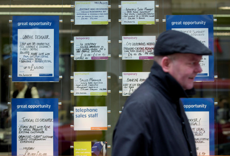 © Reuters. A man walks past job advertisements in the window of a recruitment office in central London