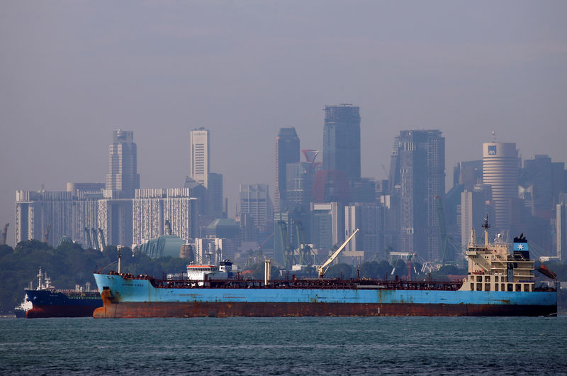 © Reuters. FILE PHOTO: Oil tankers pass the skyline of Singapore