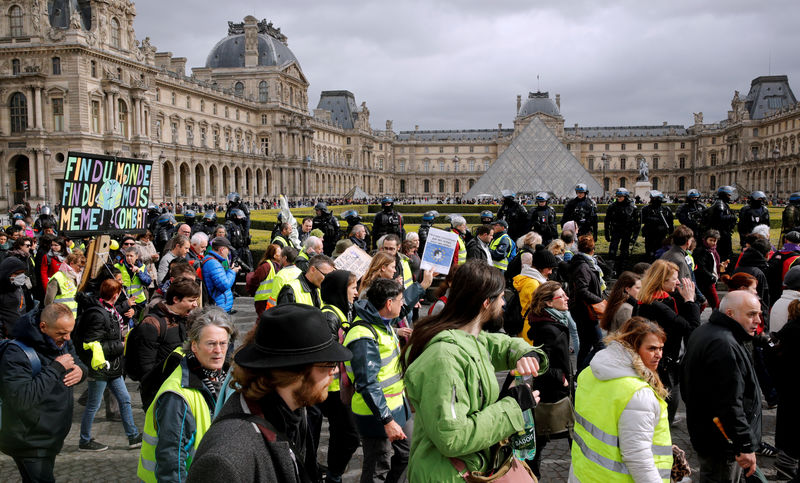 © Reuters. FILE PHOTO: Protesters wearing yellow vests pass the Louvre Museum during a demonstration by the "yellow vests" movement in Paris