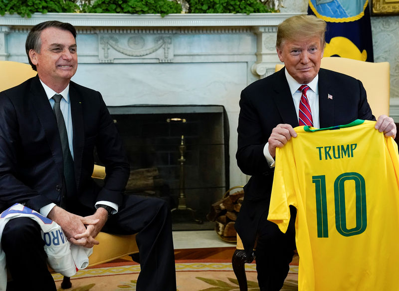 © Reuters. El presidente de Estados Unidos, Donald Trump, muestra una camiseta de la selección brasileña de fútbol entregada por su par Jair Bolsonaro, durante un encuentro entre ambos mandatarios en la Casa Blanca en Washington