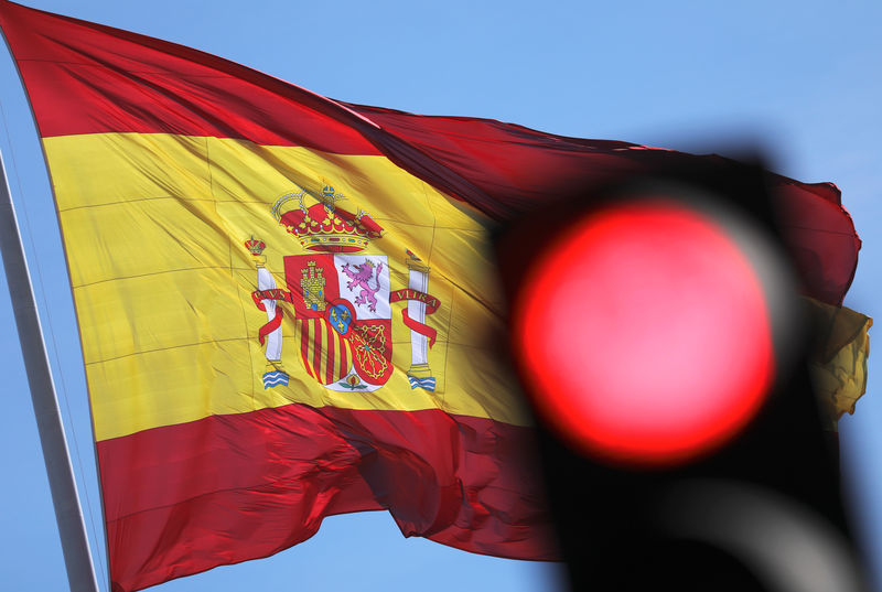 © Reuters. A Spanish flag flutters behind a red traffic light in Madrid