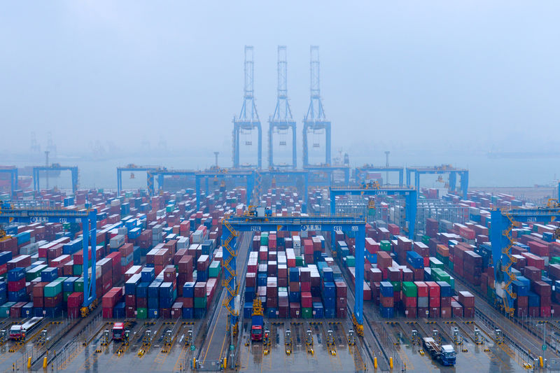 © Reuters. Caminhões e contentores em terminal no porto de Qingdao, China