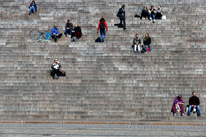 © Reuters. FILE PHOTO: People enjoy the sunny day sitting at the stairs of the Helsinki Cathedral