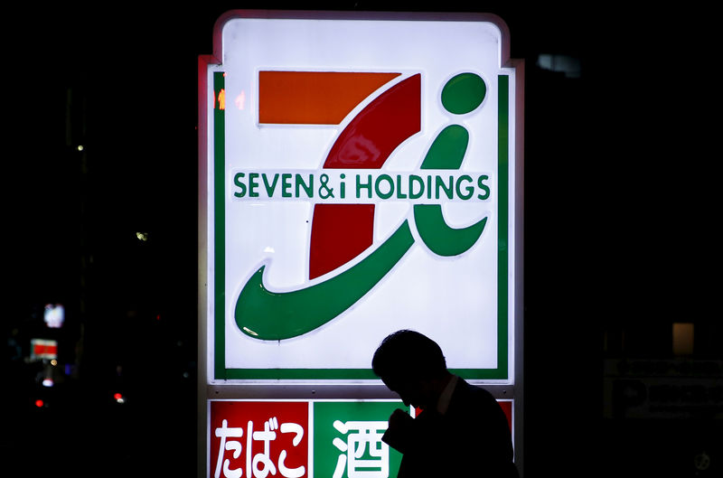 © Reuters. FILE PHOTO: A pedestrian walks in front of a signboard of Seven & I Holdings' 7-Eleven convenience store in Tokyo