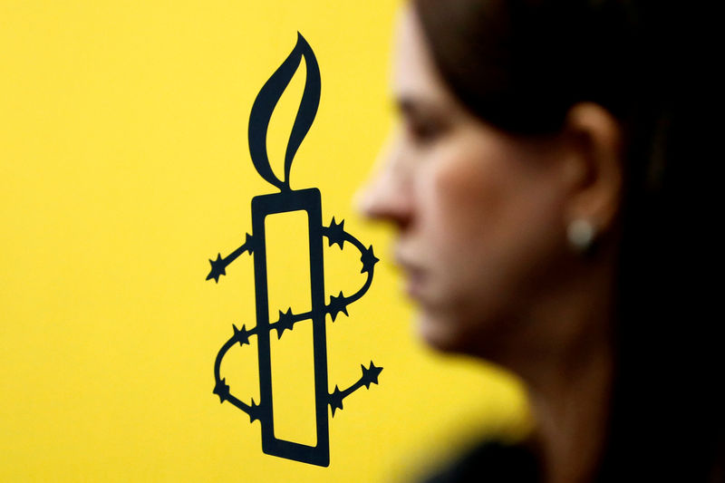 © Reuters. The logo of Amnesty International is seen next to director of Mujeres En Linea Luisa Kislinger, during a news conference in Caracas