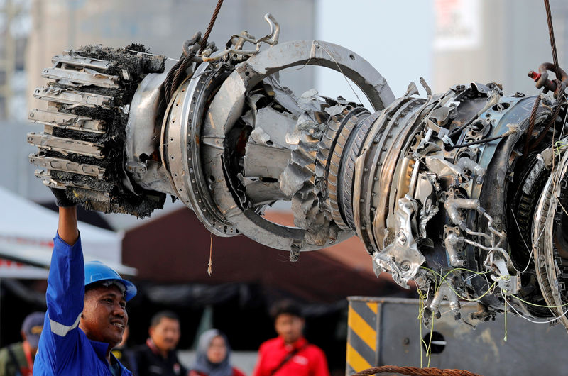 © Reuters. A worker assists his colleague during the lifting of a turbine engine of the Lion Air flight JT610 jet, at Tanjung Priok port in Jakarta