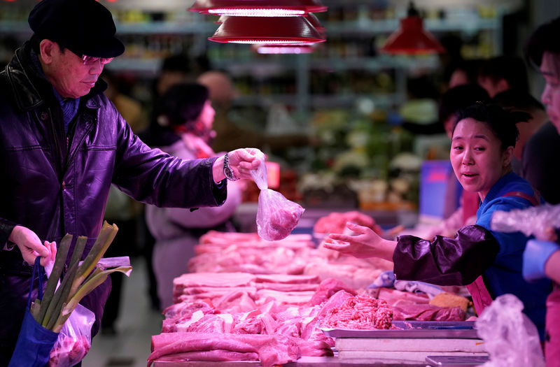 © Reuters. Um comprador recebe carne de porco de um vendedor em um mercado em Pequim