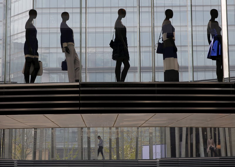 © Reuters. A man is seen walking under mannequins at a shopping mall in Beijing