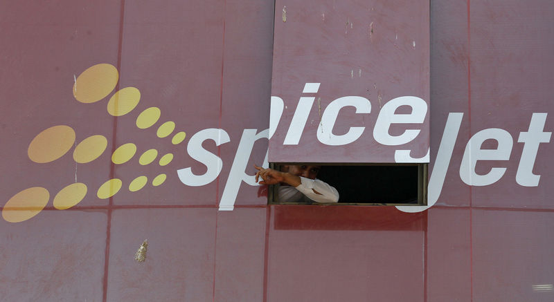 © Reuters. Man looks out through a window with an advertisement of SpiceJet Airline, on a commercial building in the western Indian city of Ahmedabad