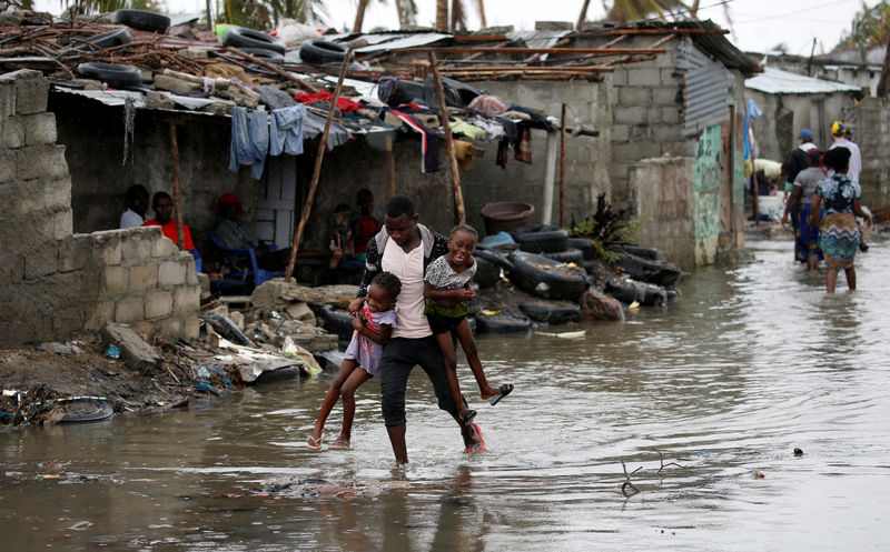 © Reuters. Un hombre lleva a sus hijos después del paso del ciclón Idai en Beira, Mozambique.