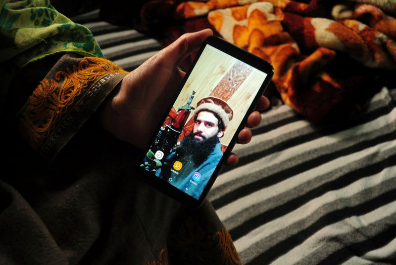 © Reuters. Sister of Owais Malik, a suspected militant, displays her phone with the picture of Malik, at her home in south Kashmir's Kulgam district