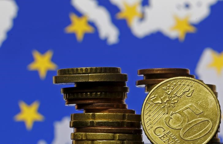 © Reuters. Moedas de euro à frente de bandeira e mapa da UE