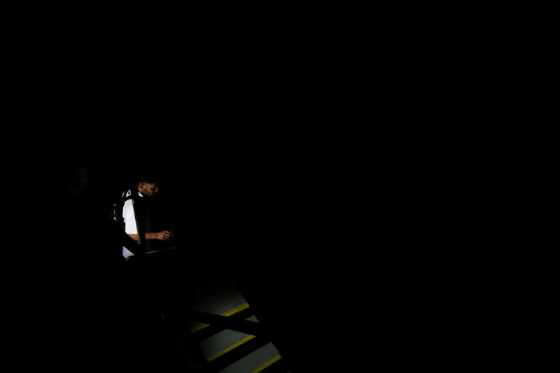 © Reuters. People use light from phones while they walk at the staircase of a building during a blackout in Caracas