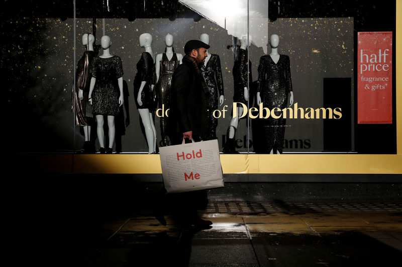 © Reuters. FILE PHOTO: Shoppers walk past a window display at the Debenhams department store on Oxford Street in London