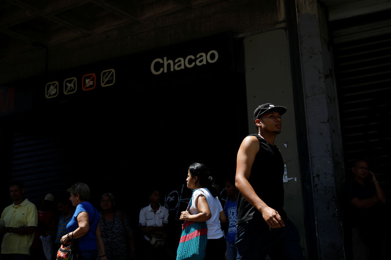 © Reuters. Transeúntes caminan frente a una estación de metro cerrada durante un apagón en Caracas
