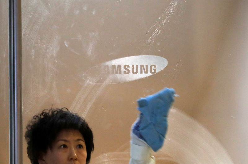 © Reuters. A worker wipes a glass panel bearing the logo of Samsung Electronics at its office building in Seoul