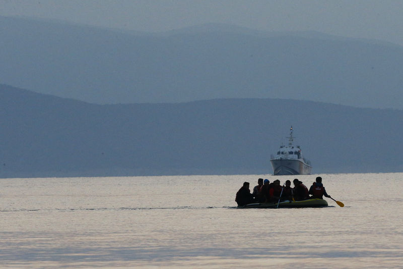 © Reuters. FOTO DE ARCHIVO: Migrantes en una balsa reman en el mar Mediterráneo mientras un barco de la Guardia Costera turca patrulla las costas de Bodrum