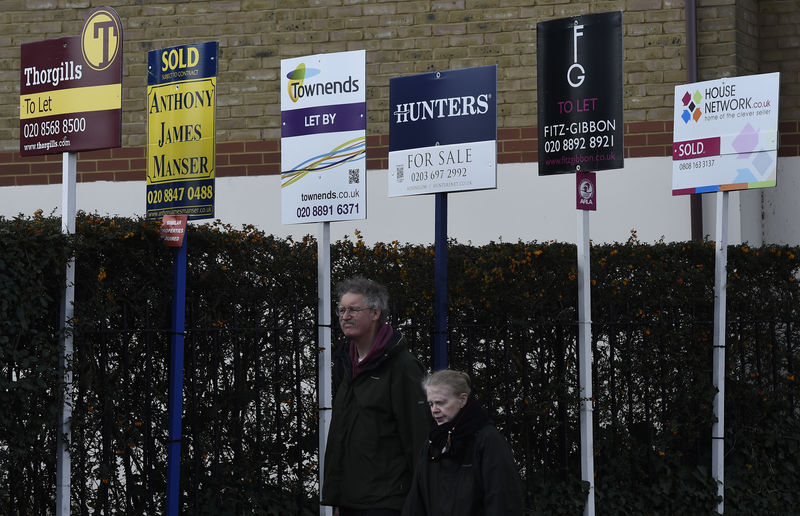 © Reuters. A couple walk past property estate agent sales and letting signs in London, Britain