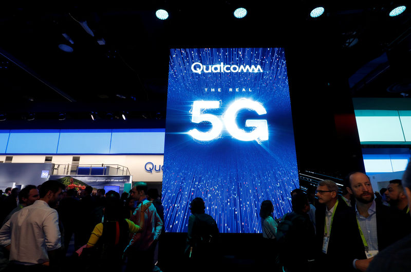 © Reuters. FILE PHOTO: People walk by a video display promoting 5G connectivity at the Qualcomm booth during the 2019 CES in Las Vegas