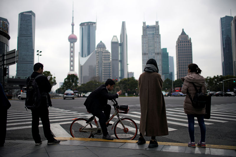 © Reuters. FILE PHOTO: People stand on the sidewalk at Lujiazui financial district in Pudong, Shanghai