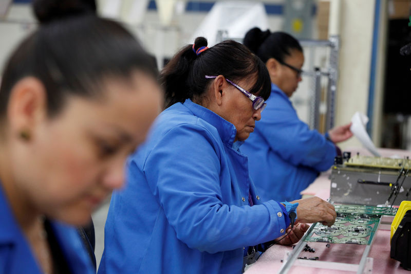 © Reuters. FILE PHOTO: Employees work on a printed circuit board at the assembly line of a factory that exports to the U.S. in Ciudad Juarez