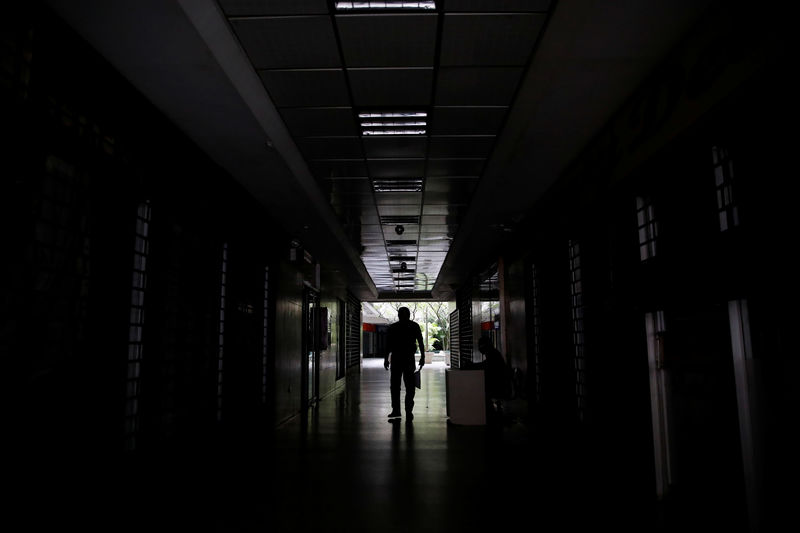 © Reuters. Un hombre camina por el pasillo de un edificio durante un apagón en Caracas