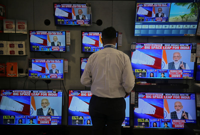 © Reuters. Un vendedor mira al Primer Ministro Narendra Modi dirigiéndose a la nación, en las pantallas de TV dentro de una sala de exposición en Mumbai, India.