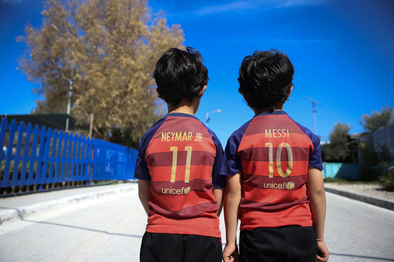 © Reuters. FOTO DE ARCHIVO: Niños refugiados visten camisetas del FC Barcelona en Mytilene, en la isla de Lesbos