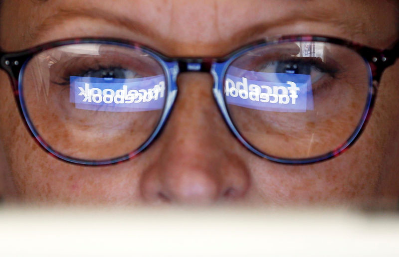 © Reuters. The Facebook logo is reflected on a woman's glasses in this photo illustration