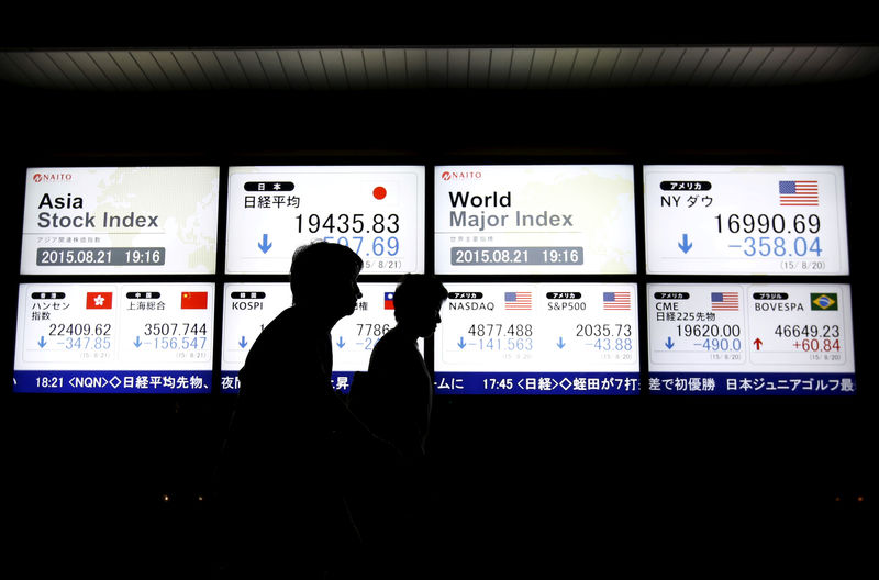 © Reuters. Pessoas caminham em frente a painel com informações de movimentos de mercados