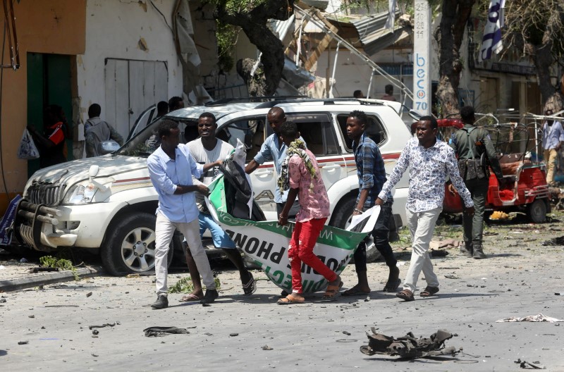 © Reuters. Civis carregam corpo de vítima de explosão de carro-bomba perto de hotel de Mogadíscio