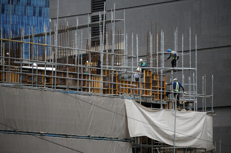 © Reuters. FILE PHOTO: Workers labour on steel frames at a construction site in central Seoul