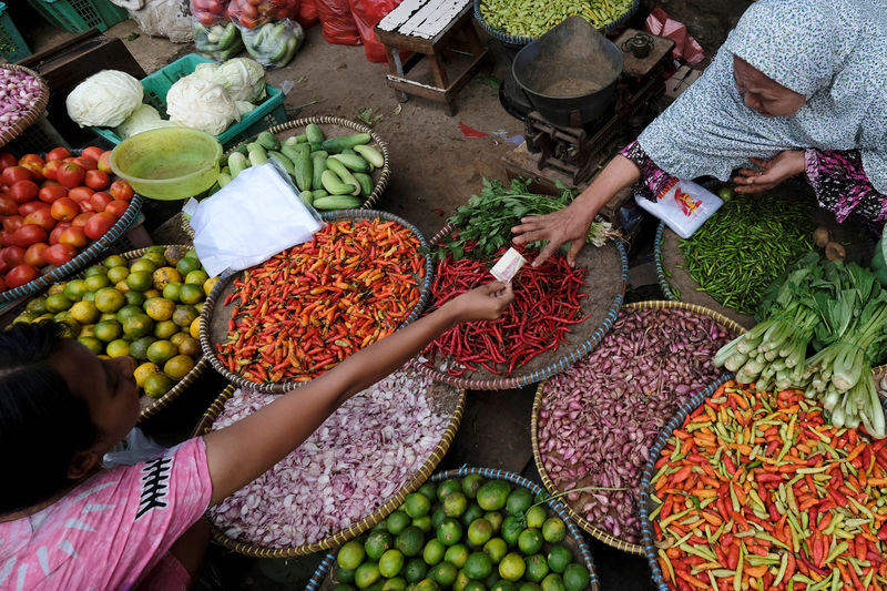 © Reuters. A vegetable seller reaches for money from a customer at a market in Jakarta