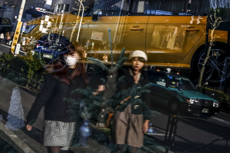 © Reuters. Women are reflected in the window of a car dealer as they walk in a shopping district in Tokyo