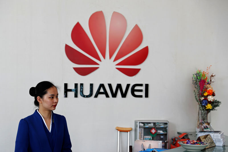 © Reuters. An employee stands next to the logo of Huawei in Shenzhen