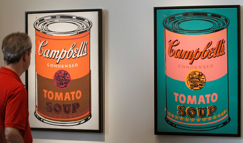 © Reuters. FILE PHOTO: A man looks at two paintings 'Coloured Campbell's soup can' by late U.S. artist Andy Warhol the Art Unlimited of the Art Basel art fair in Basel